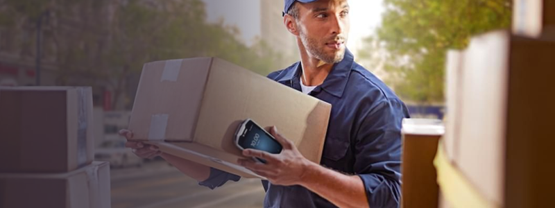 Delivery driver loading boxes into a truck while holding a handheld device that is managed and secured by SOTI MobiControl, which is Zebra Solution Validated