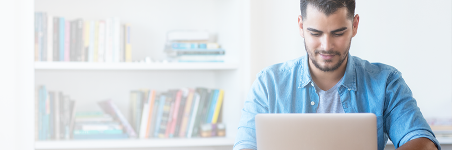 Young man sitting at a home office working on a laptop computer