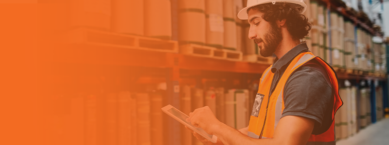 Male warehouse worker taking inventory on a handheld tablet