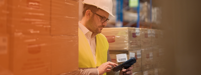 Warehouse worker using a barcode scanner to track inventory for distribution