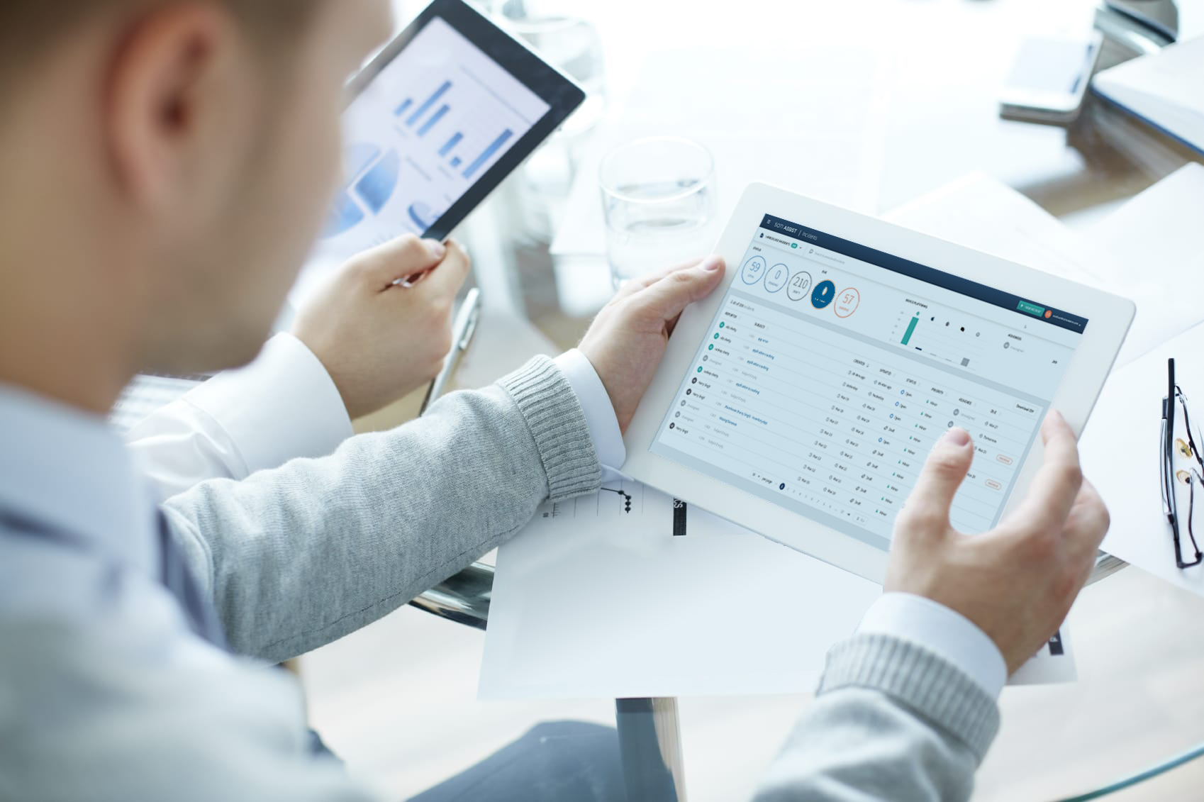 Man holding an Apple tablet with SOTI Assist detailed device logs displayed on screen