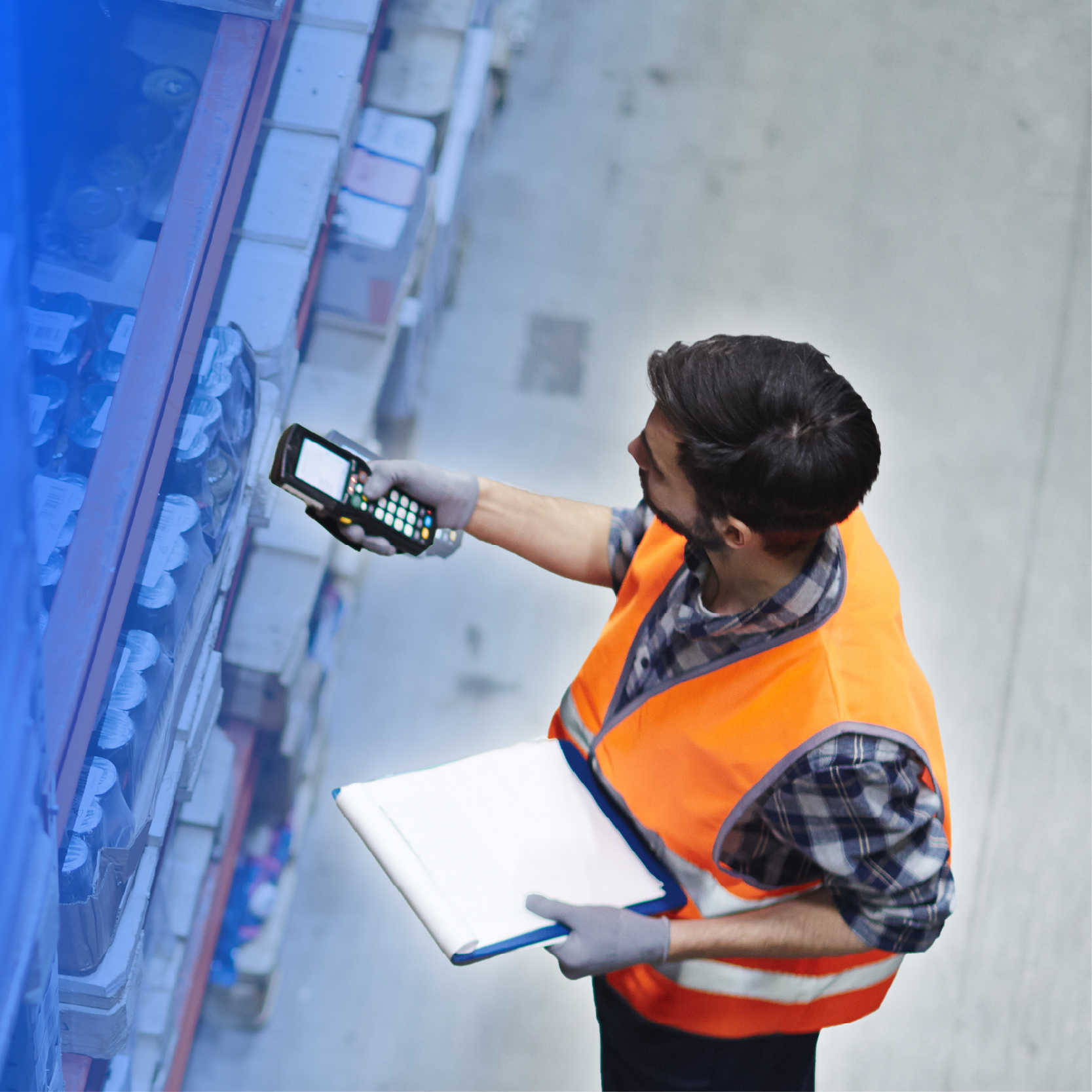 Man wearing a safety vest, in a warehouse, holding a scanner