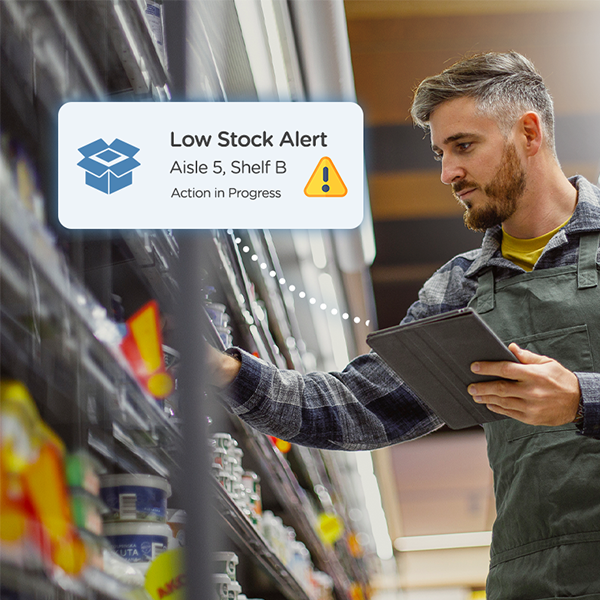 Retail associate using a tablet and restocking a shelf